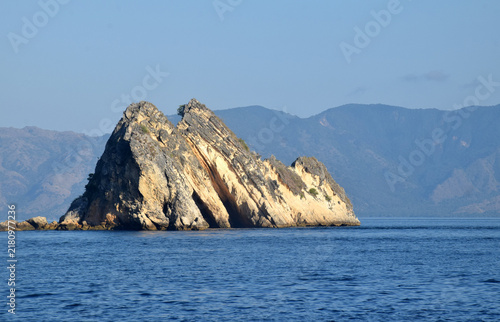 Sailing to Komodo Island in clear weather, passing rugged hills amidst the crystal-clear waters of Rinca Island, Labuan Bajo, Indonesia.