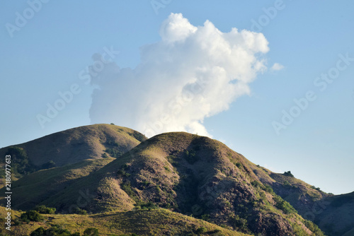 Sailing to Komodo Island in clear weather, passing rugged hills amidst the crystal-clear waters of Rinca Island, Labuan Bajo, Indonesia.