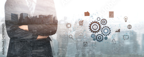 Obraz na plátne Professional business person standing confidently with urban skyline and digital gears overlay symbolizing technology and innovation in the corporate world
