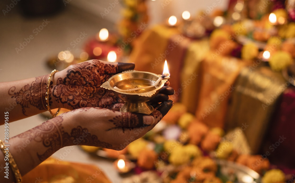 Obraz premium Woman with henna on hands holding a lit oil lamp for celebration