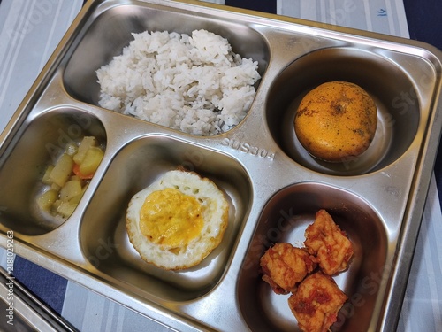 School cafeteria tray with rice fried egg muffin and fried chicken in compartments
