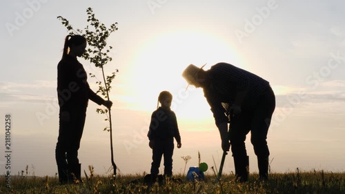 Parents guide planting, Kids learn by example, Hands in earth, Family values shared, Sunset kids activity, Teaching earth care, Outdoor bonding, Tree of future, Planting at dusk, Nature family goals