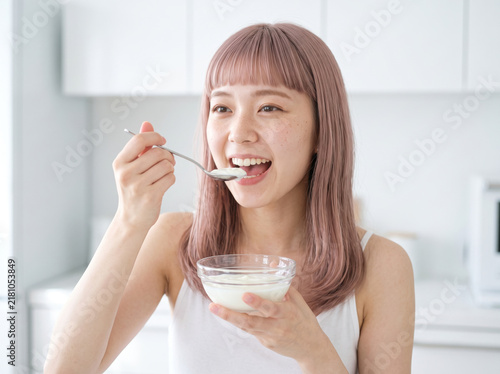 Obraz na płótnie 明るい朝の部屋でヨーグルトを食べる若い日本人女性
