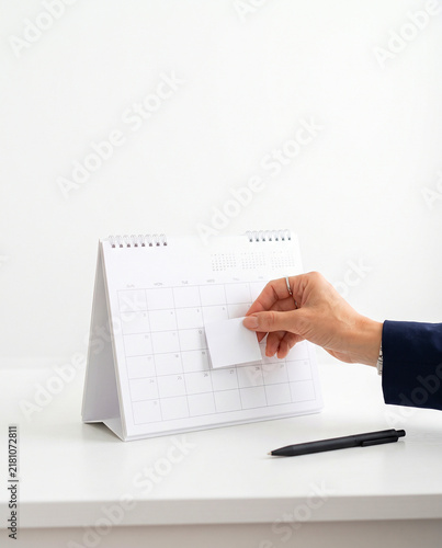 Hand Placing Sticky Note on Blank Desk Calendar Stand Mockup
