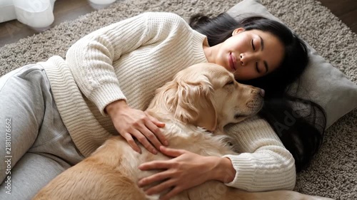 Young Woman Lying on Rug and Hugging Golden Retriever Dog. 4K Video