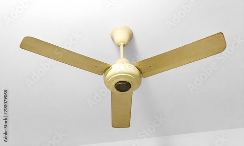 Beige three blade vintage ceiling fan mounted on plain white ceiling low angle view