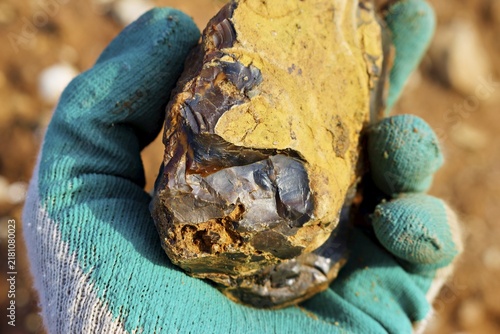 Foto Close-up of a rough dark flint stone shard with a textured yellow crust held in