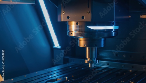 Close-up of a CNC milling machines cutting tool in a dark industrial environment with blue lighting.
