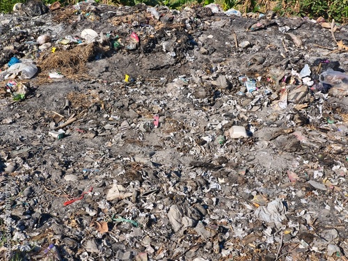 Fotografía A smoking pile of burning garbage and plastic waste dumped outdoors on dirt, highlighting environmental pollution, ecological crisis, climate change, and waste management issues