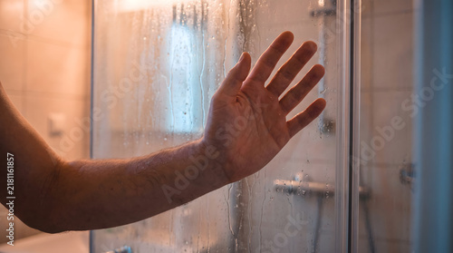 Hand pressed against steamy wet shower glass dealing with mental health crisis anxiety disorder and suffocating panic