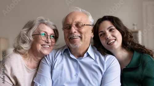 Bild auf Leinwand Portrait of happy senior grandparents and young adult granddaughter laughing at home