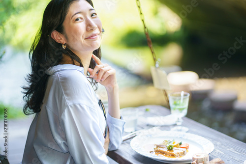 Obraz na płótnie Japanese woman turning back with a smile at a streamside cafe table set with a m