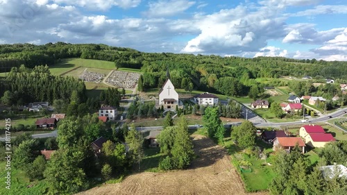 Aerial mountain village Lutcza church southern Pola. South eastern Poland. Historic mountain valley village with 15th century wooden All Saints Church. Agriculture land, rivers, forest and rural farm.