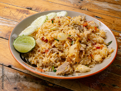 Obraz na płótnie Thai Pork Fried Rice with Cucumber Slices and Lime on Rustic Wooden Table, Homes
