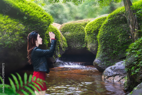 A young Asian female tourist admires the beauty of a dolphin-shaped rock at Phu Langka National Park, Bueng Kan Province, Thailand.