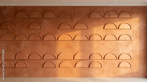 Terracotta wall with repeating semi-circular architectural details and warm sunlight.