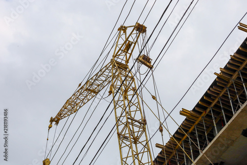 Foto A yellow tower crane rises beside the reinforced concrete building frame under an overcast sky