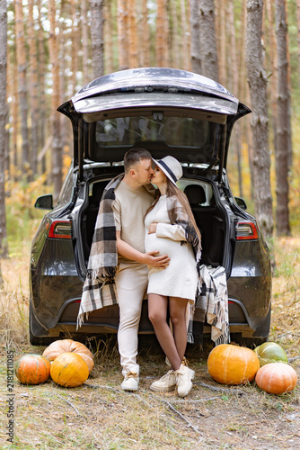 A loving couple shares a tender moment during their maternity photoshoot in a beautiful forest setting