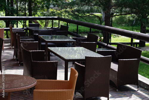 Foto Outdoor wicker furniture set with table by a stream in a lush garden