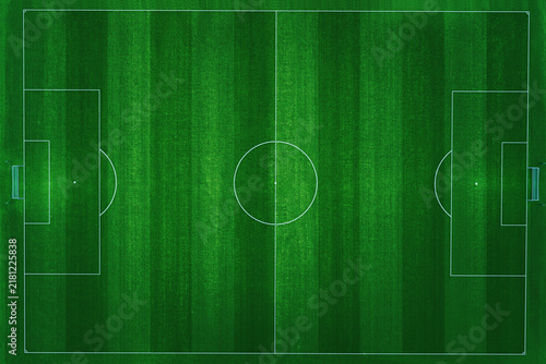 Aerial top-down view of a professional football field with vibrant green grass and clear white markings. The pitch is empty, perfectly manicured, and ready for a soccer match in a stadium at night.