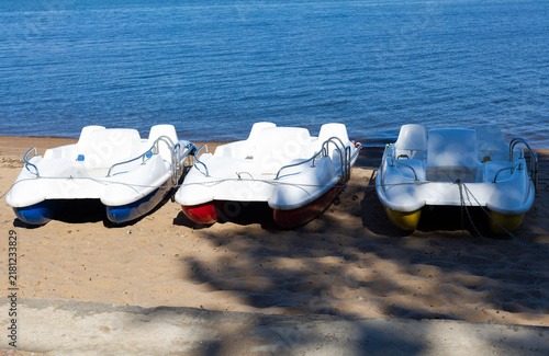 Obraz na płótnie Three small leisure boats pulled ashore on sandy beach with calm blue sea under