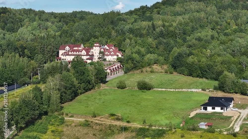 Aerial mountain Monastery Blizne southern Poland. South eastern Poland. Historic mountain valley village with 15th century wooden All Saints Church. Agriculture land, rivers, forest and rural farm.