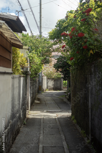 Plakat w ramie 家々の影が道路にある天気の良い街の細い路地裏