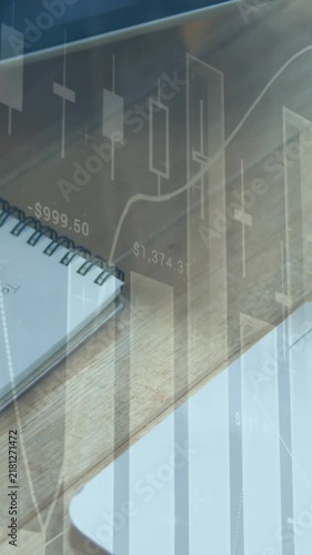 Animation of multiple graphs, overhead view of caucasian man writing in notepad on desk