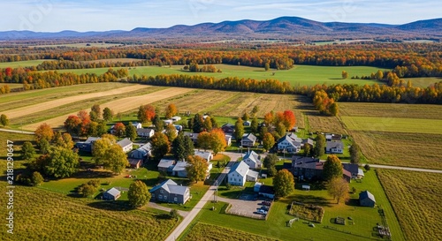 Autumnal aerial view of a tranquil rural village nestled amidst colorful fall foliage and rolling hills.