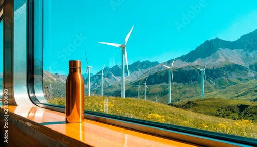View from a train window showing a water bottle and wind turbines in the mountains