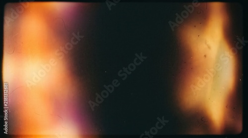 Vintage film light leak overlay with dust and scratches on dark background, featuring nostalgic retro aesthetic and warm analog burn effect for video editing and cinematic photo filter design.