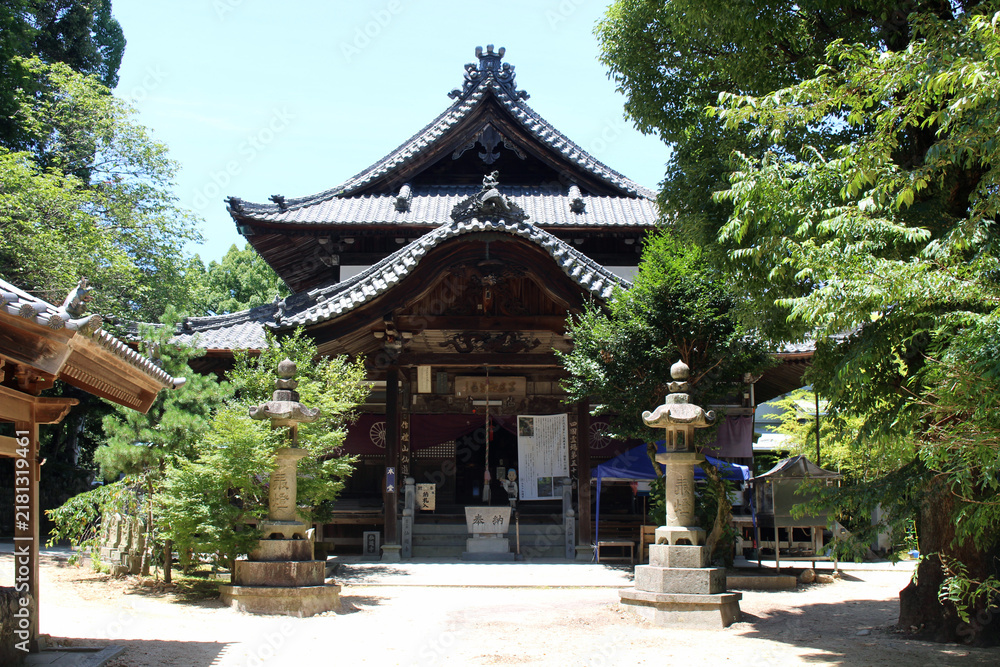 Fototapeta premium Hondo Main Hall and Stone Lanterns Courtyard at Senyuji Temple (Temple 58) on Shikoku Henro Pilgrimage, Ehime 2026