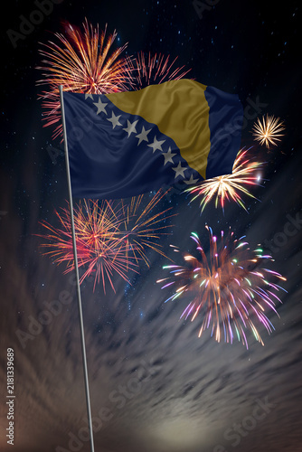 Waving National flag of Bosnia Herzegovina and holiday fireworks in night sky
