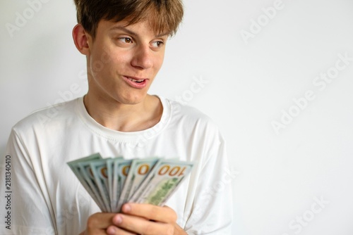 Konstfotografi A surprised and successful young caucasian teenager proudly holding a lot of cash money in his hands, concept of first earnings, financial success and smart investments