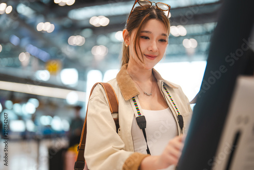 Asian woman traveler woman using self service check in counter kiosk machine for boarding pass airplane ticket at nternational airport terminal