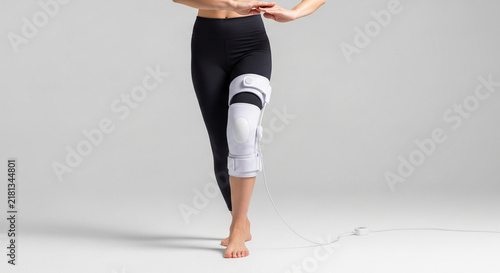 Woman wearing a white minimalist bio-feedback knee stabilizer brace for orthopedic support and rehabilitation