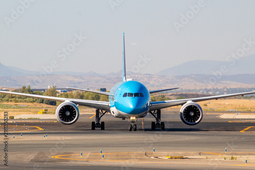 Foto Wide-body jet aircraft taxiing head-on at an international airport, showing engi