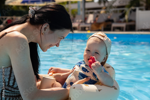 фотографія Mother and baby enjoying a sunny day playing in a bright blue swimming pool