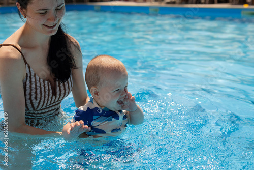 Bild auf Leinwand Mother and baby enjoying a refreshing swim together in a bright blue swimming po