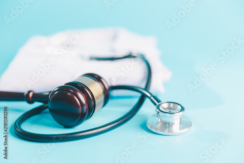 Картината върху платно Judge gavel and stethoscope on a blue surface with a white medical coat behind,
