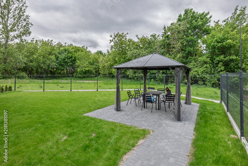 Cuadro en lienzo Modern Gazebo With Outdoor Dining Set on Paved Patio in Green Backyard Garden