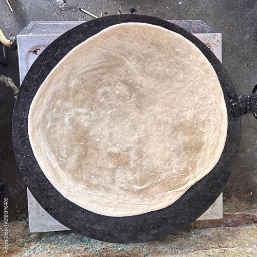 Fresh traditional Indian chapati roti cooking on a hot black tawa griddle pan