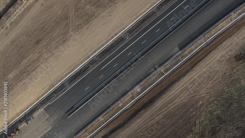 Top down aerial view of Autostrada Moldovei A7 Nod Bacau construction site showing fresh asphalt lanes, heavy road building machinery, and infrastructure progress. 4K video.