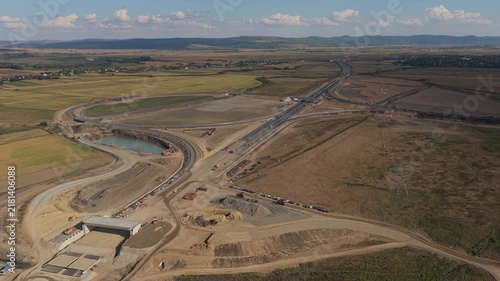 Aerial panoramic view of highway construction at Autostrada Moldovei A7 junction near Bacau under bright daylight, highlighting modern infrastructure development. 4K video.