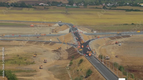 Aerial view of heavy machinery constructing the Autostrada Moldovei A7 highway junction near Bacau, showcasing modern infrastructure development under bright sunlight. 4K video.