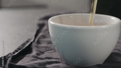 Slow motion pour black tea in white cup closeup with copy space