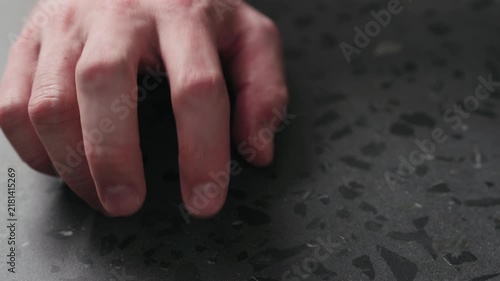 Slow motion closeup man finger tapping on terrazzo countertop