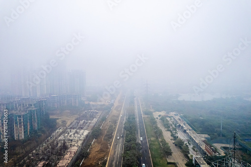 Aerial view of Tulip Chowk featuring a highway surrounded by high-rise buildings, construction sites, and heavy smog in Gurugram, Haryana, India.