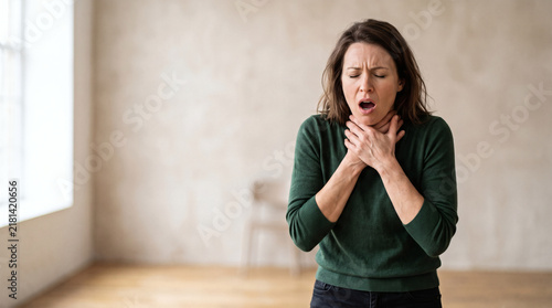 choking emergency woman clutching throat in distress panic attack medical crisis beige studio background photorealistic 8k dramatic lighting wide angle hyper realistic detail sharp focus professional