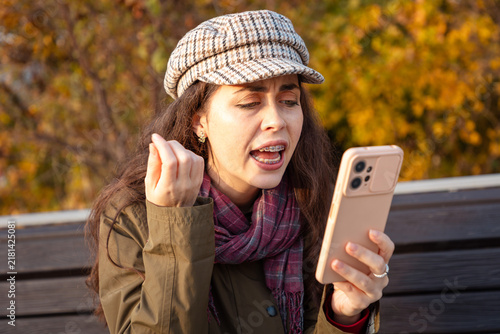 Foto Young Caucasian woman expressing outrage during a smartphone conversation